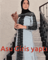 a woman wearing a hijab is standing on stairs holding a bouquet of flowers