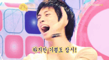 a young man is making a funny face with korean writing on the bottom right corner
