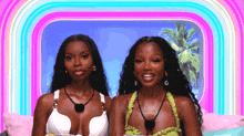 two women are posing for a picture in front of a rainbow