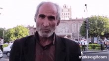a man with a beard is standing in front of a building on a city street .