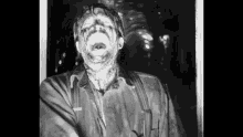 a black and white photo of a man with his mouth open and his face covered in blood .