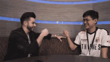 a man wearing a thieves shirt shakes hands with another person
