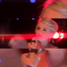 a woman is singing into a microphone in a dark room