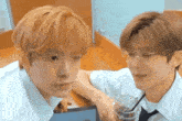 two young men are sitting next to each other in a room .