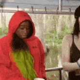 a woman wearing a red hoodie is standing next to another woman .