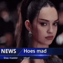 a woman with a ponytail and earrings is standing in front of a news banner that says hoes mad