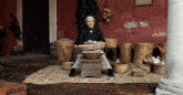 a woman sits in front of a red wall holding a bowl of food