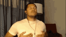 a man wearing headphones and a white shirt is standing in front of a red chair .