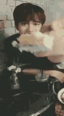 a young boy is sitting at a table eating a sandwich and drinking a drink .