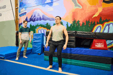 a man stands on a balance beam in front of a mural that says hard