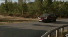 a red car is driving down a road with a sign in the background that says ' renault '