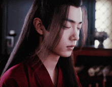 a man with long hair is wearing a red robe