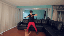 a man in sunglasses is dancing with a dog in front of a couch