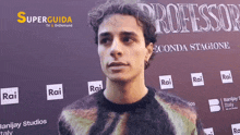 a man stands in front of a wall that says professor on it