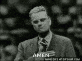 a man in a suit and tie is praying with his hand on his heart .