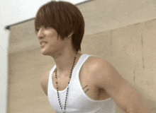 a man with red hair is wearing a white tank top and a necklace