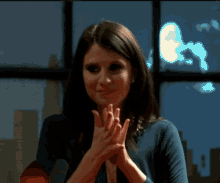 a woman in a blue shirt is clapping her hands