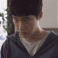 a close up of a young man wearing a blue hoodie and a white shirt .