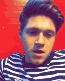 a man wearing a black and white striped shirt is making a face