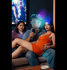 a man is singing into a microphone while a woman sits on a man 's lap