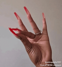 a close up of a woman 's hand with long red nails