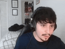 a man with a mustache is wearing headphones while sitting in a chair .