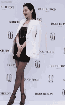 a woman in a black dress is standing in front of a wall that says boucheron