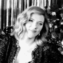 a black and white photo of a woman wearing a sequined dress .
