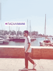 a man walking in front of a harbor with a sign that says pasalimani