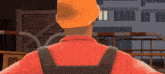 a man wearing an orange hard hat and a red shirt stands in front of a building