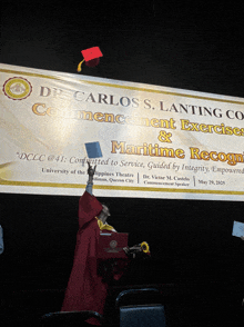 a graduate throws his cap in the air in front of a banner that says carlos s. lanting co