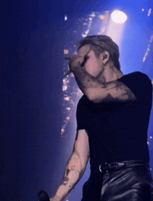 a man with a tattoo on his arm holds his hand over his face