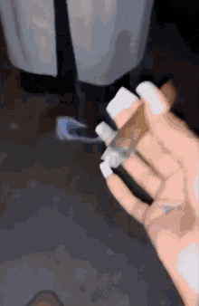 a person with long white nails is holding a lighter in their hand