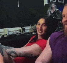 a woman in a red shirt is sitting next to a man in a purple shirt and smiling