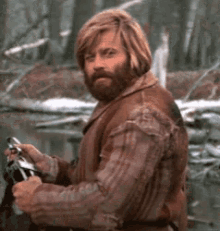 a man with long hair and a beard is holding a fishing rod