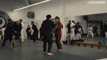 a group of people are practicing martial arts in a gym with #karatekidmovie written on the wall behind them