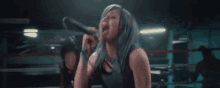 a woman is singing into a microphone in a ring .