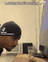 a man in a beanie is looking at a computer screen with a caption that says " lowkey had it coming "