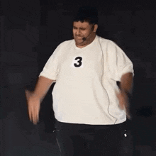 a man wearing a white shirt with the number 3 on it is dancing .