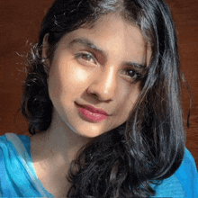 a close up of a woman 's face wearing a blue top