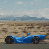 a blue car is driving down a road in the desert