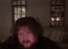 a blurry picture of a man 's face in a dark room with a window behind him .