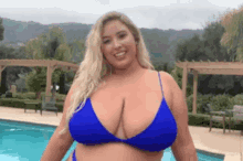 a woman in a blue bikini is standing in front of a pool .