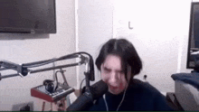a woman is screaming into a microphone while sitting in front of a television in a room .