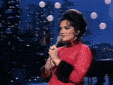 a woman in a red sweater is singing into a microphone .