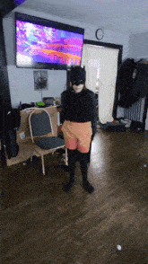 a person in a batman costume standing in front of a tv