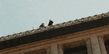 two men are standing on the roof of a building with a blue sky in the background