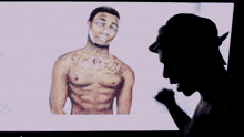 a man is looking at a picture of a shirtless man with tattoos