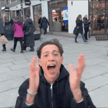 a man with his mouth open and his hands in the air stands in front of a store that says signs