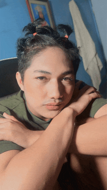 a young man with a ponytail and a green shirt looks at the camera